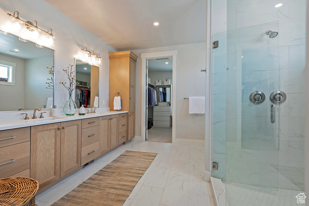 Bathroom with tile patterned floors, double sink vanity, and a shower with door