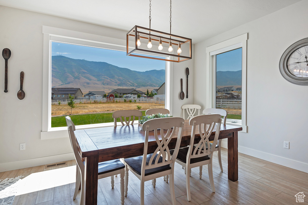 Dining room with a mountain view, an inviting chandelier, and wood-type flooring