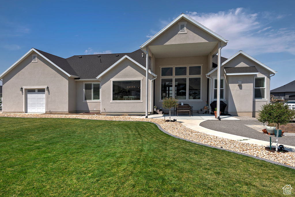 Exterior space featuring a garage, a patio, and a lawn