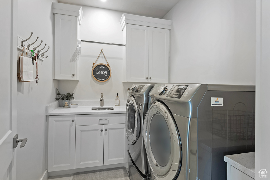 Laundry area featuring cabinets, washing machine and dryer, and sink