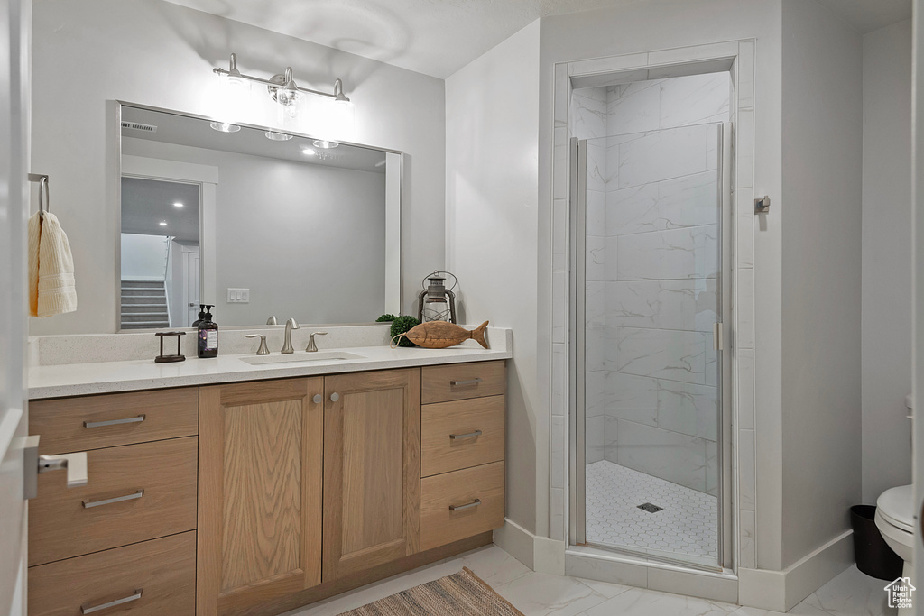 Bathroom featuring tile patterned flooring, a shower with door, toilet, and vanity