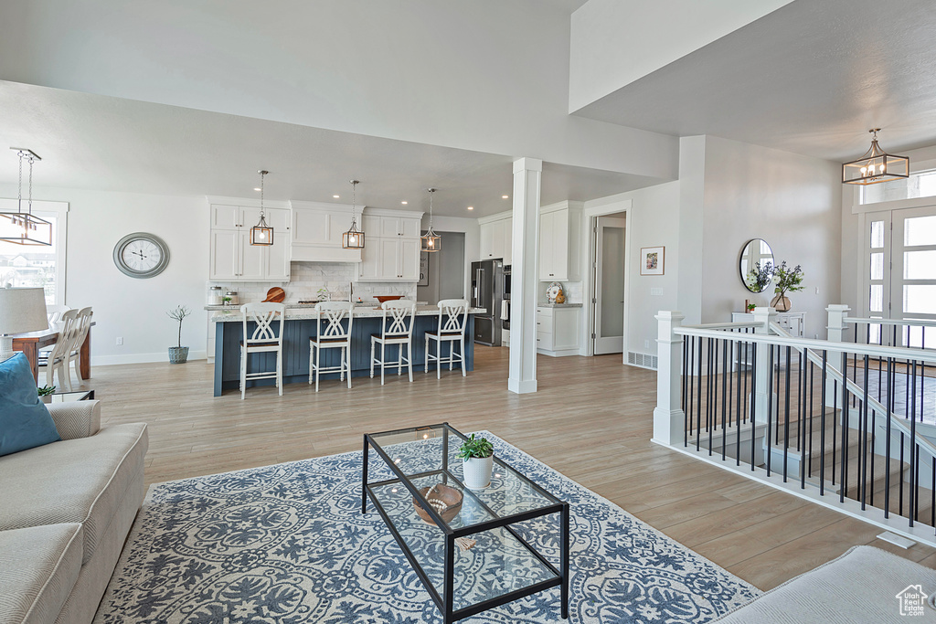 Living room with decorative columns, light wood-type flooring, and a chandelier