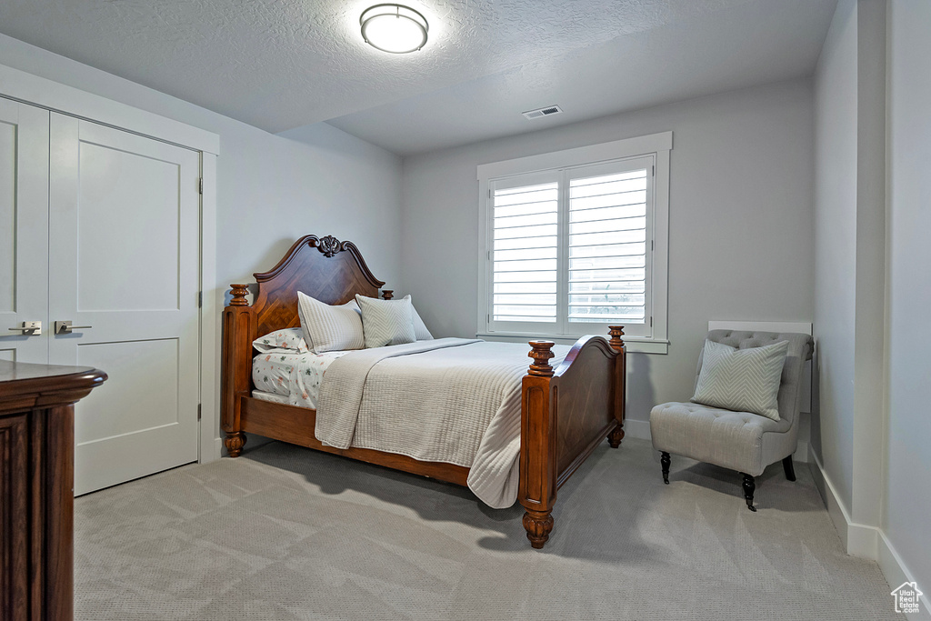 Bedroom featuring a textured ceiling and light colored carpet