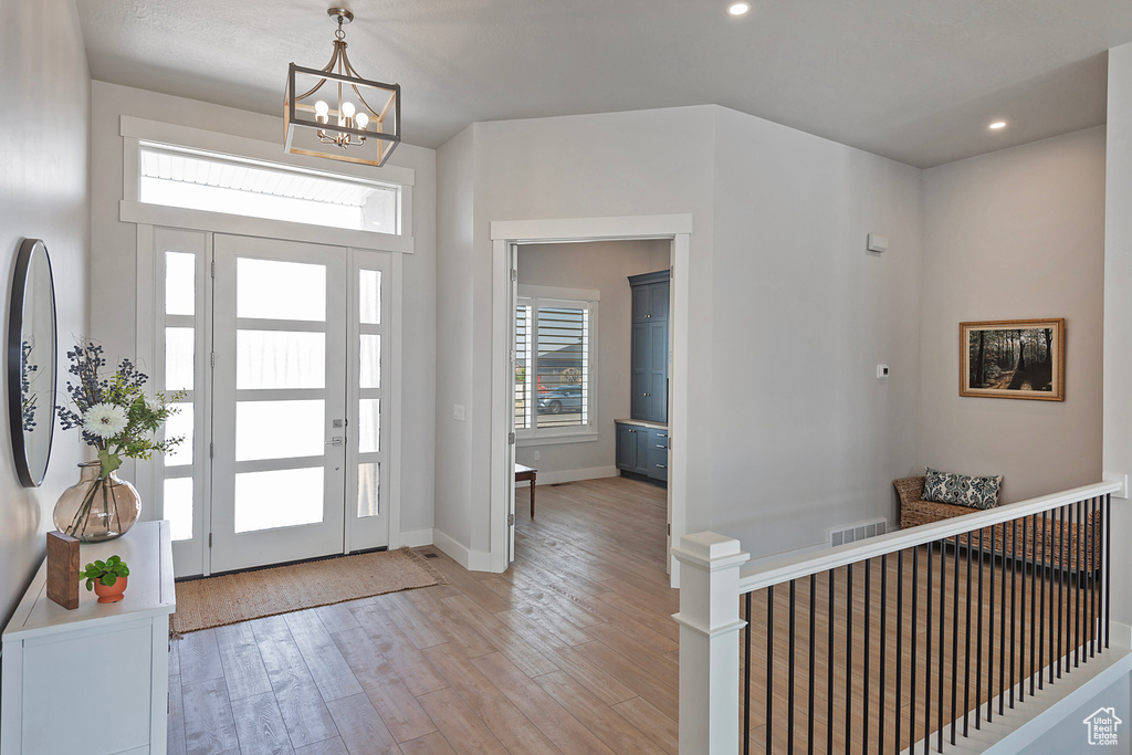 Entrance foyer featuring light hardwood / wood-style floors and a notable chandelier