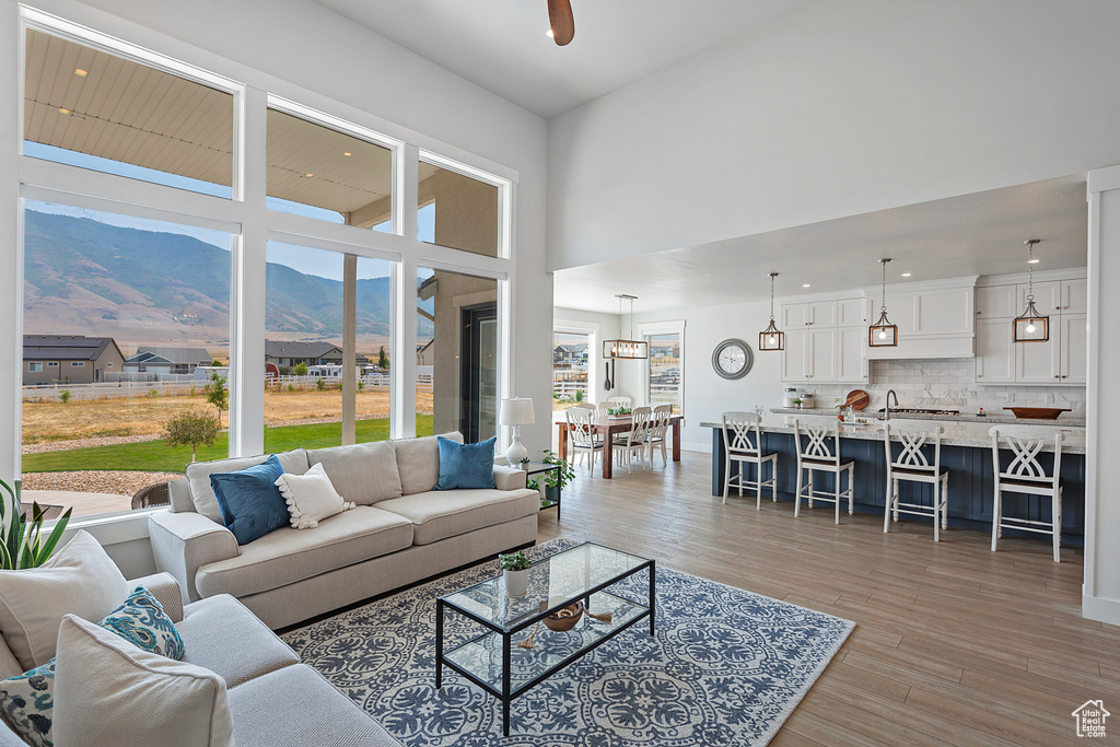 Living room with light wood-type flooring, a mountain view, and a towering ceiling