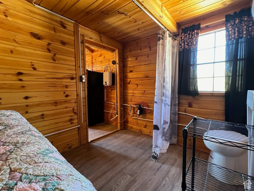 Bedroom with dark wood-type flooring, wooden walls, and wooden ceiling