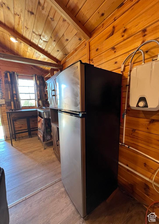 Kitchen with lofted ceiling, stainless steel refrigerator, wood walls, wooden ceiling, and hardwood / wood-style flooring