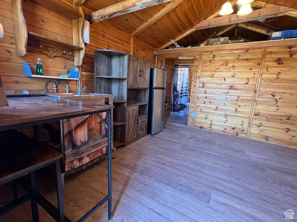 Interior space with stainless steel fridge, wood-type flooring, vaulted ceiling with beams, and wood ceiling