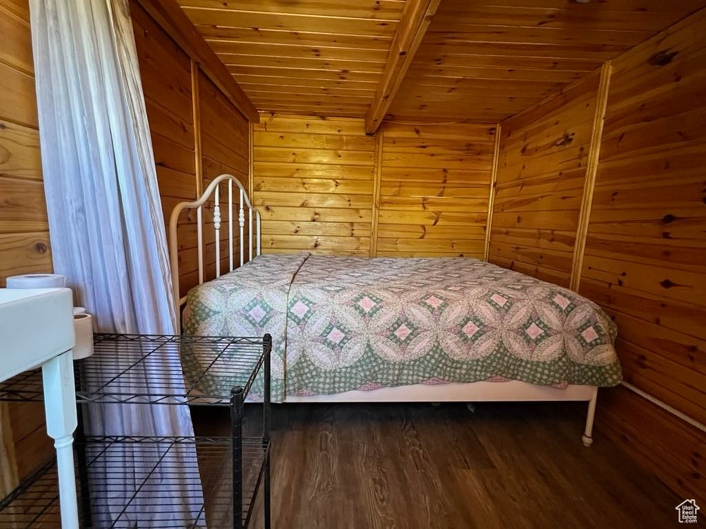 Bedroom featuring beamed ceiling, wood walls, hardwood / wood-style floors, and wood ceiling