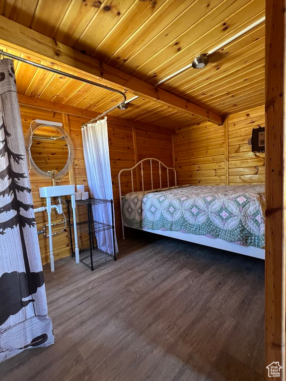 Unfurnished bedroom featuring beam ceiling, wooden ceiling, wooden walls, and dark wood-type flooring