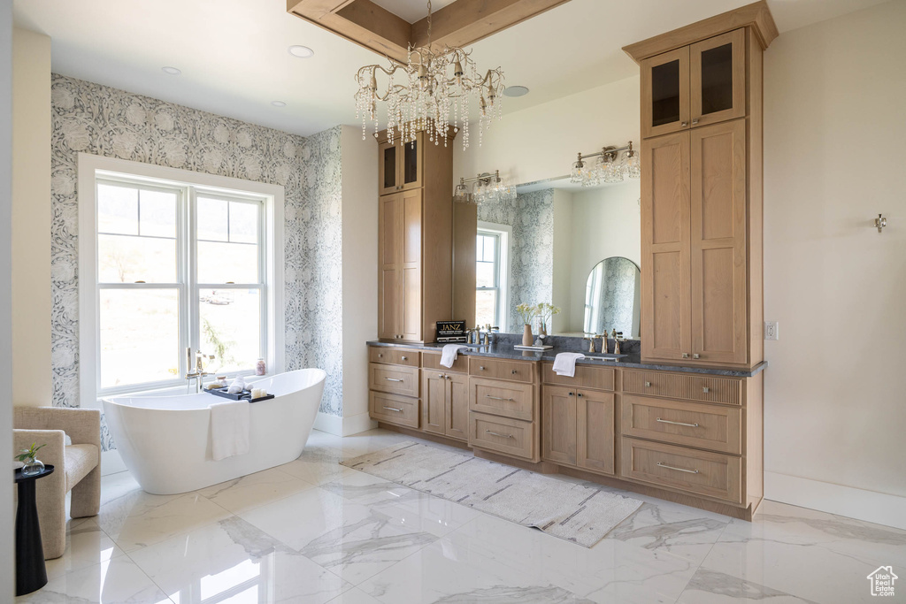 Bathroom with dual vanity, tile patterned floors, a bathing tub, and an inviting chandelier