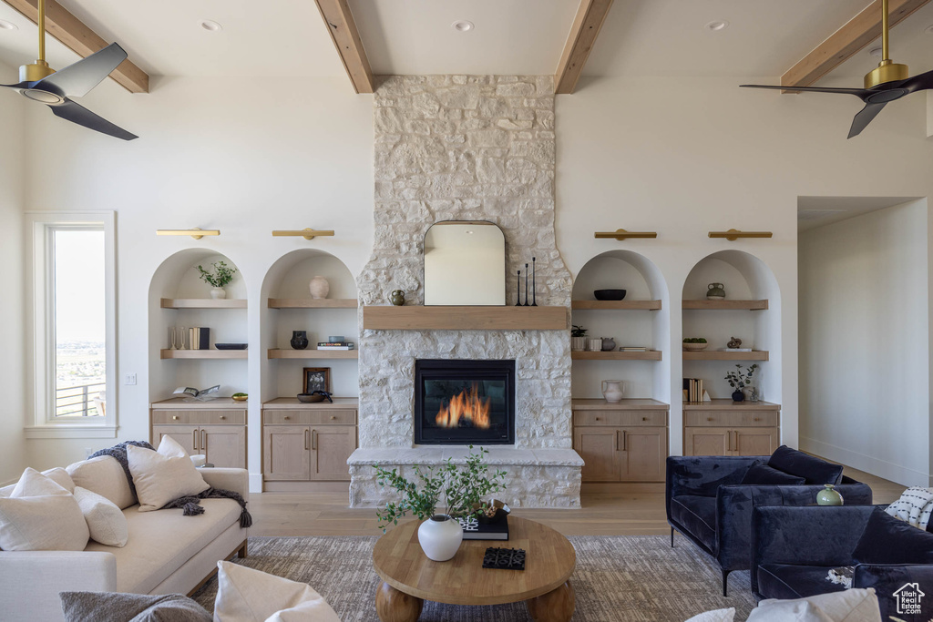 Living room featuring a fireplace, ceiling fan, light hardwood / wood-style floors, and beam ceiling