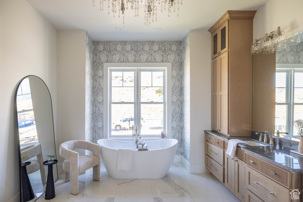 Bathroom featuring a washtub, tile patterned floors, vanity, and an inviting chandelier