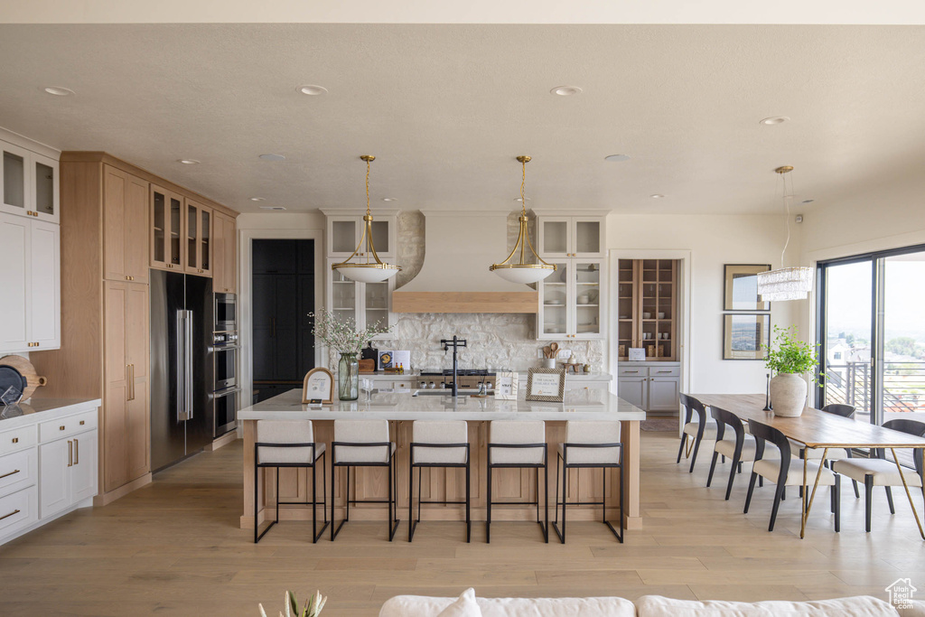 Kitchen featuring sink, decorative light fixtures, and a center island with sink