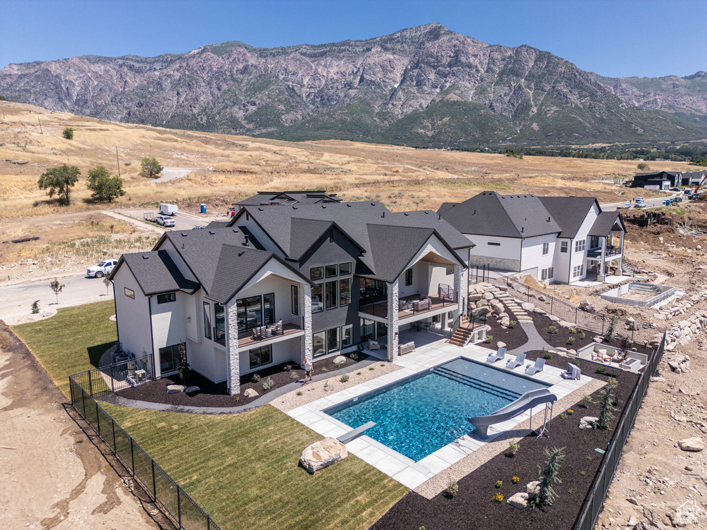 View of pool featuring a mountain view, a diving board, a patio area, and a lawn