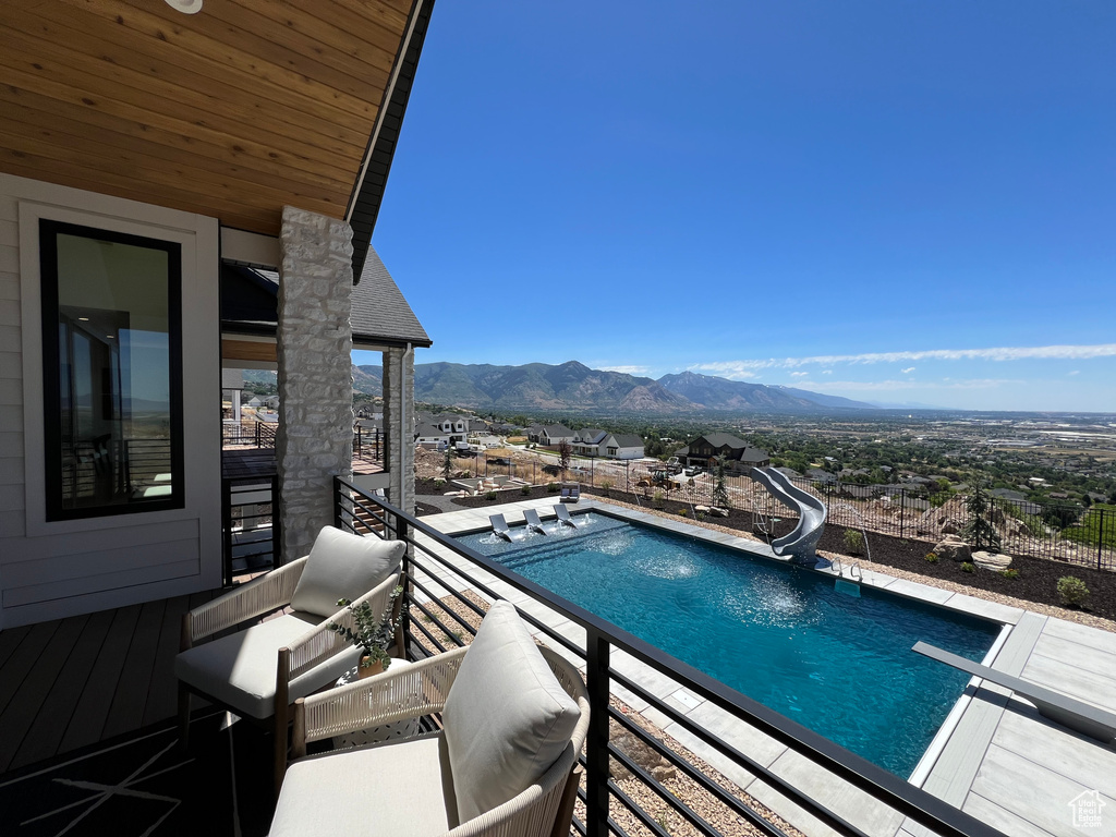 View of pool featuring a diving board, a water slide, and a mountain view