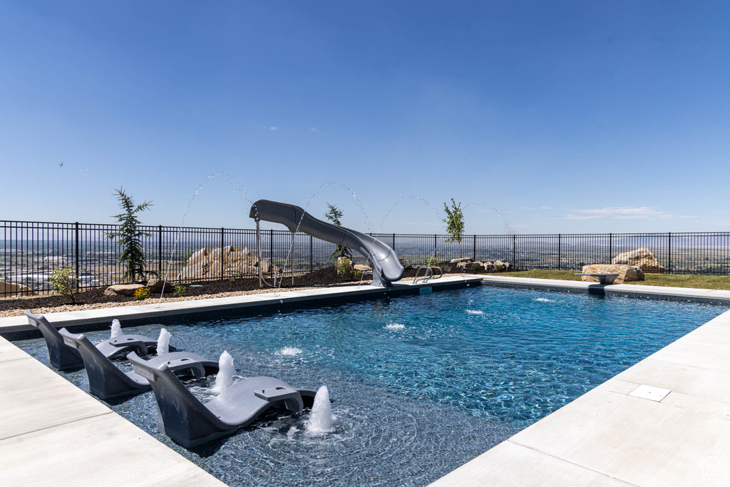 View of swimming pool with a water slide and pool water feature