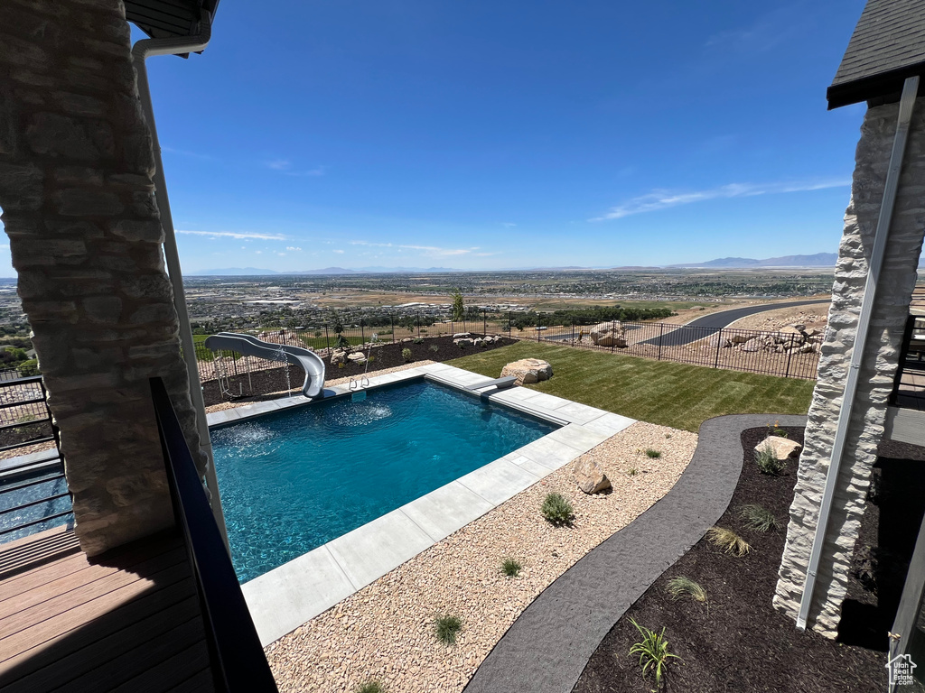 View of pool with a water slide and a yard