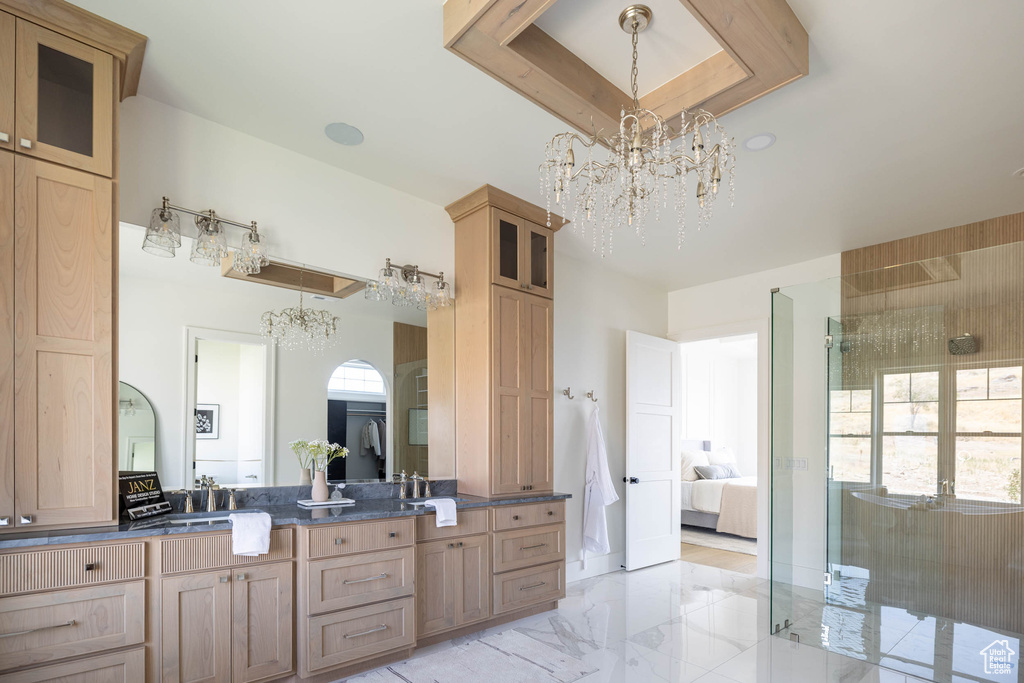 Bathroom featuring tile patterned floors, double sink vanity, walk in shower, a tray ceiling, and a chandelier