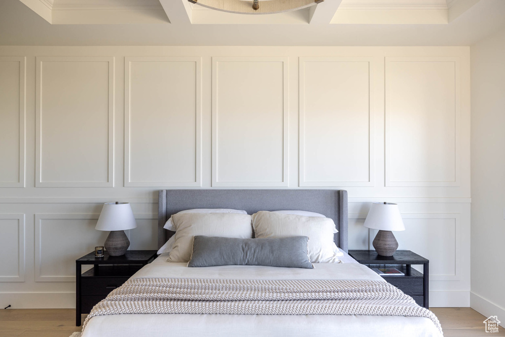 Bedroom with crown molding, light hardwood / wood-style flooring, and a raised ceiling