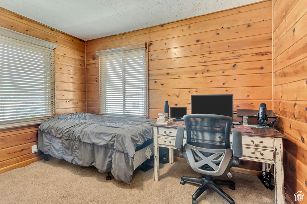 Bedroom featuring light colored carpet and wooden walls