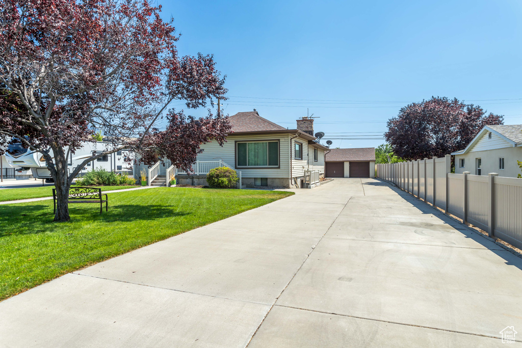 View of front of home with a garage, an outdoor structure, and a front yard