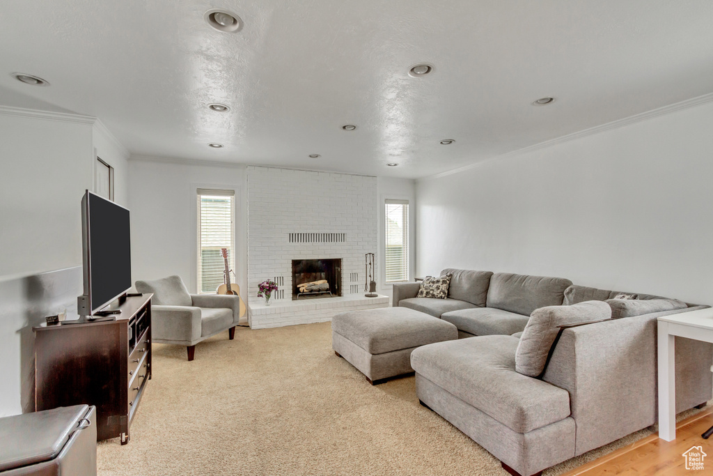 Carpeted living room featuring brick wall, crown molding, and a brick fireplace