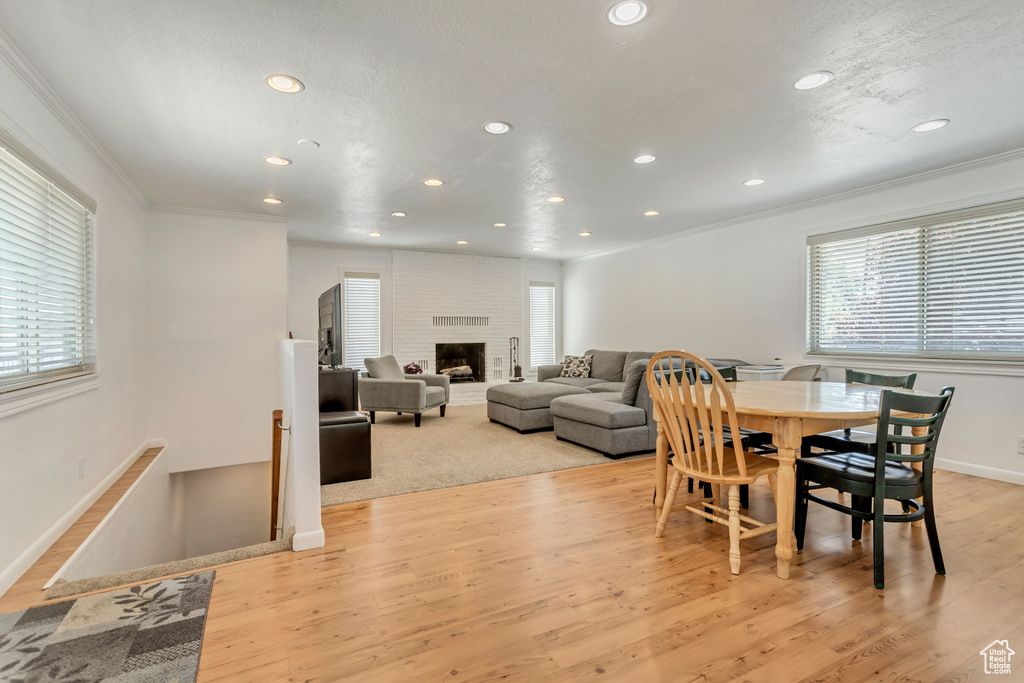 Dining space with crown molding, a fireplace, and light hardwood / wood-style flooring