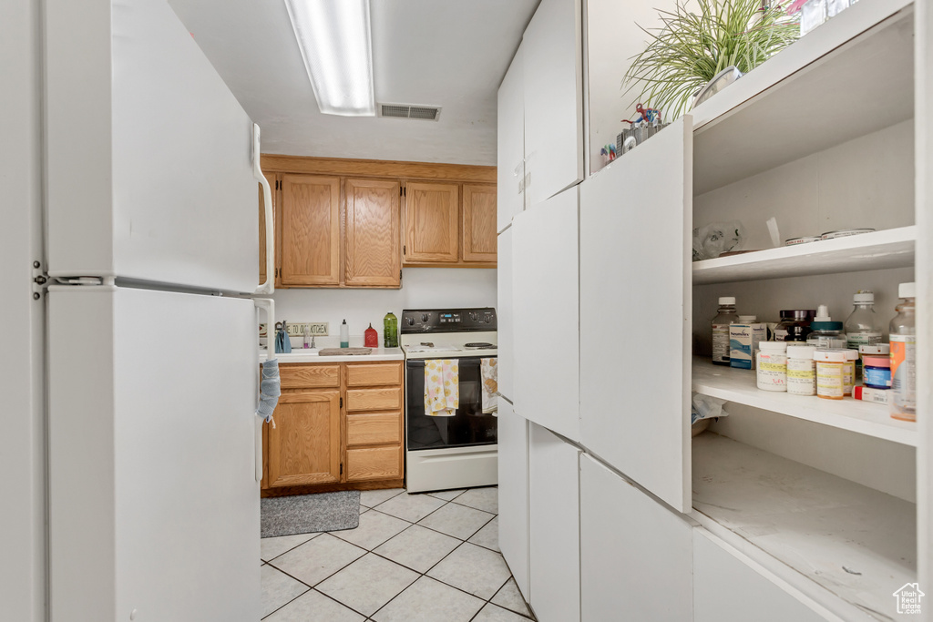 Kitchen featuring light tile patterned flooring and white appliances