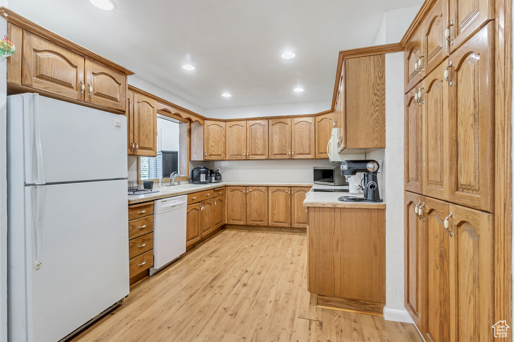 Kitchen featuring light hardwood / wood-style flooring, white appliances, and sink