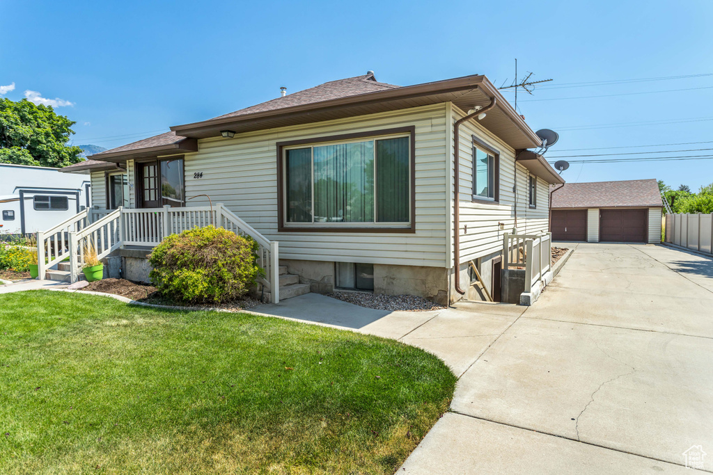 View of front of property with an outbuilding, a garage, and a front lawn