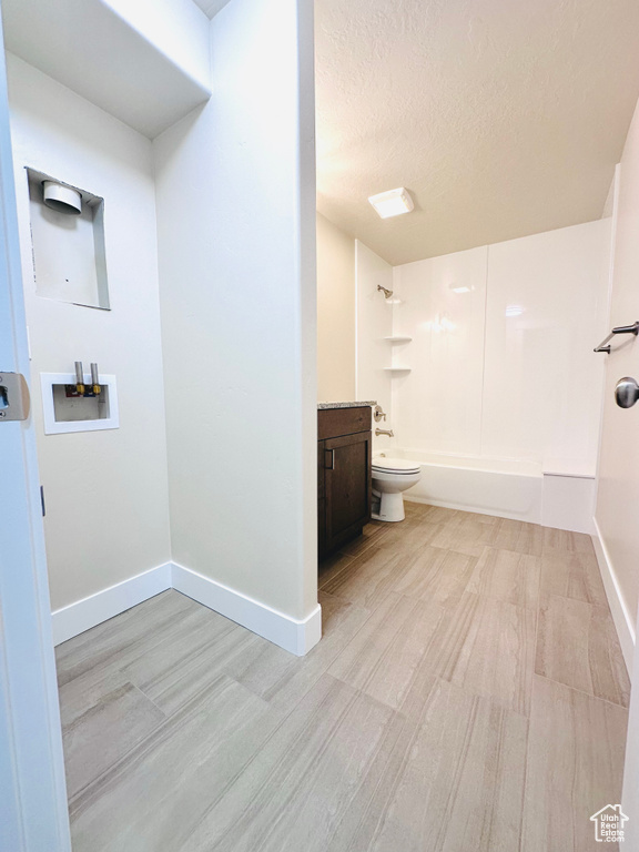 Full bathroom with hardwood / wood-style flooring, toilet, shower / bath combination, vanity, and a textured ceiling