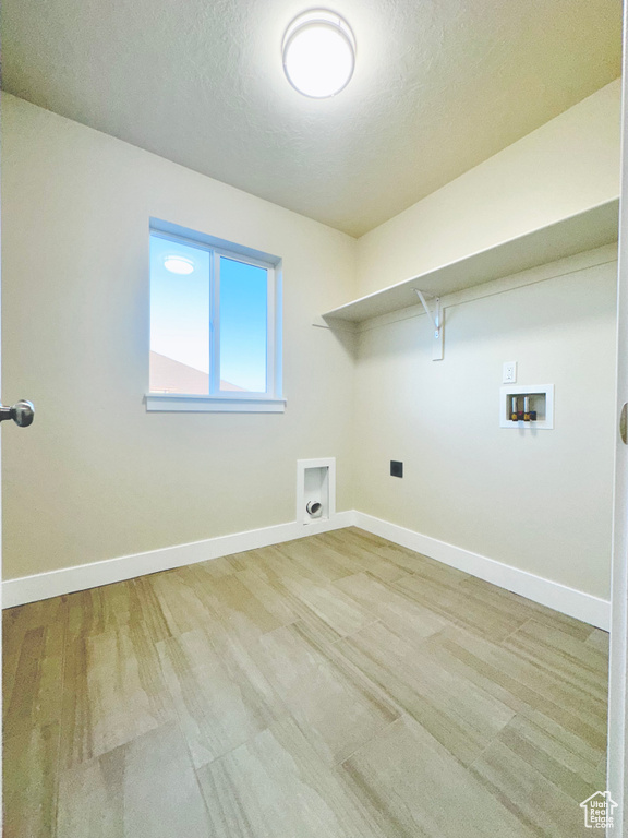 Laundry area featuring hookup for a washing machine, a textured ceiling, and light hardwood / wood-style floors