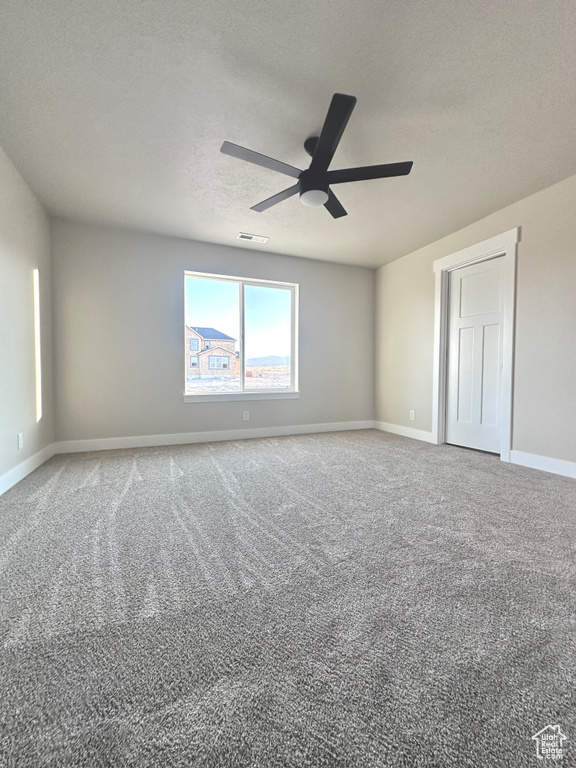 Carpeted empty room with a textured ceiling and ceiling fan