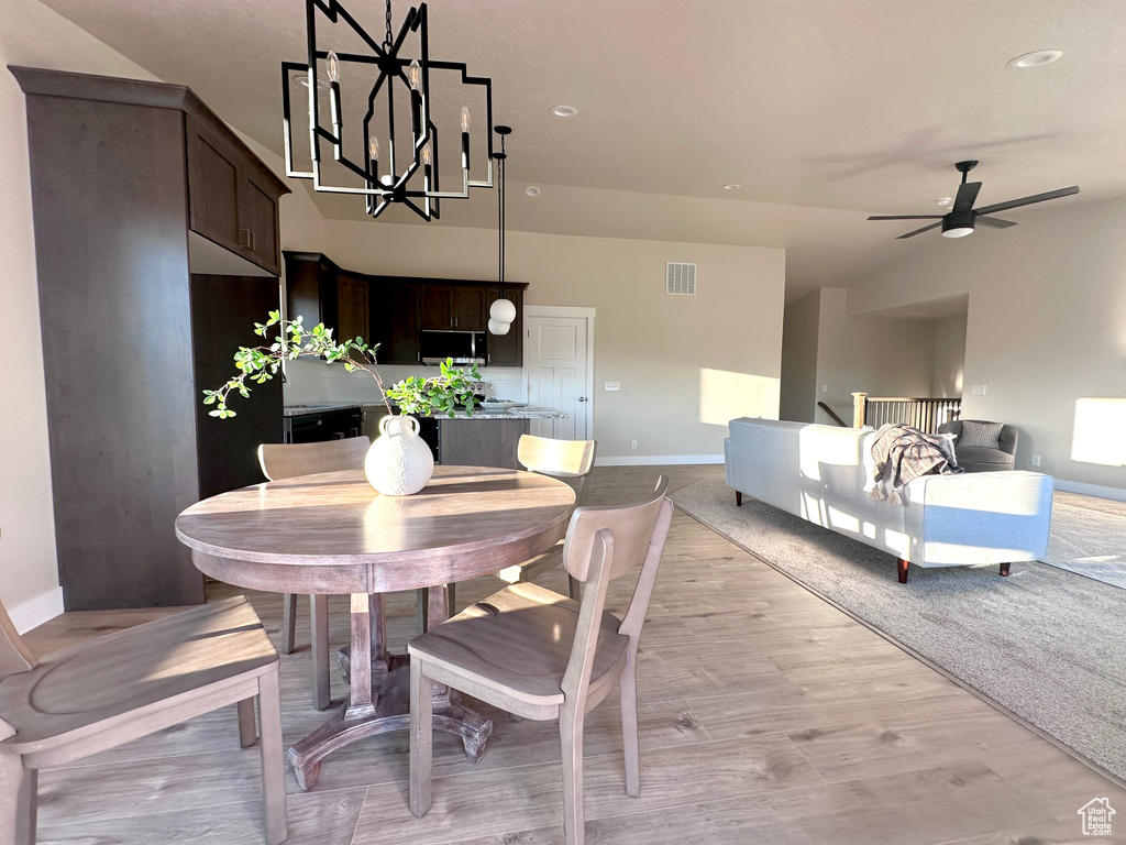 Dining room with light hardwood / wood-style flooring and ceiling fan with notable chandelier