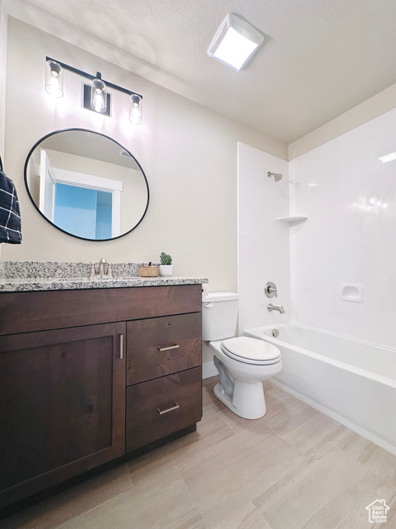 Full bathroom with vanity, a textured ceiling, bathing tub / shower combination, and toilet