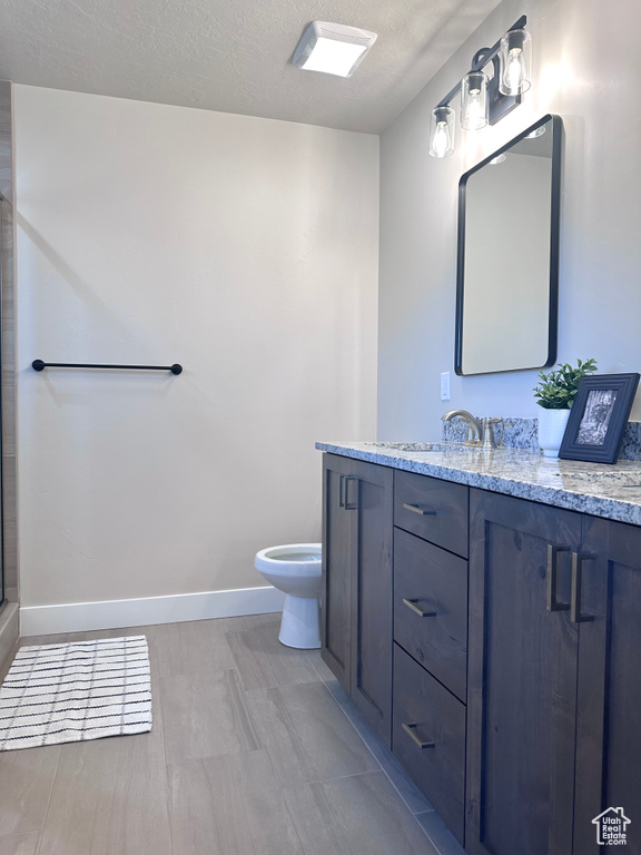 Bathroom with vanity, toilet, and a textured ceiling