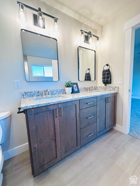 Bathroom with vanity, toilet, and a textured ceiling