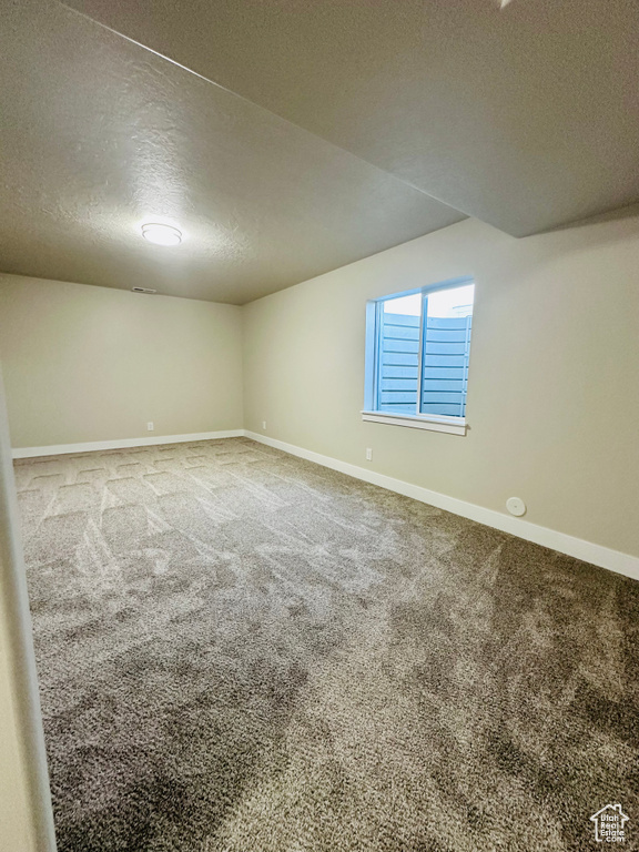 Carpeted spare room with a textured ceiling