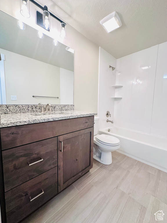 Full bathroom featuring vanity, toilet, a textured ceiling, and  shower combination