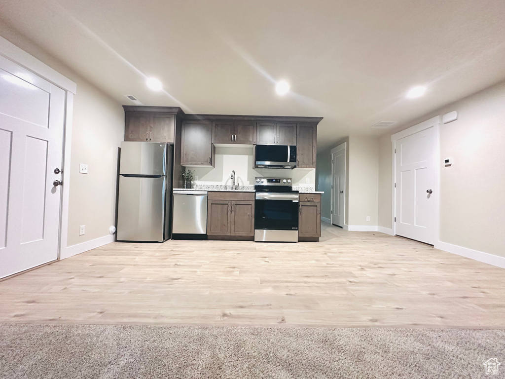 Kitchen featuring appliances with stainless steel finishes, sink, and light wood-type flooring