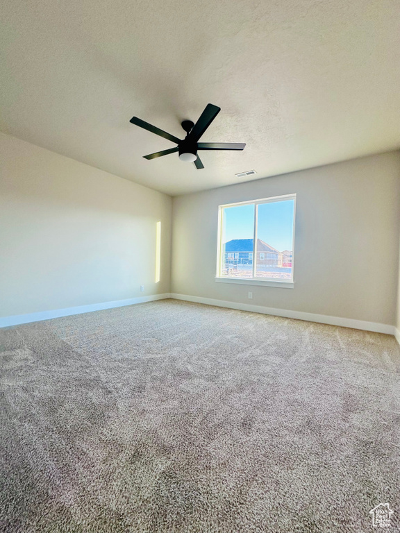 Carpeted empty room with ceiling fan and a textured ceiling