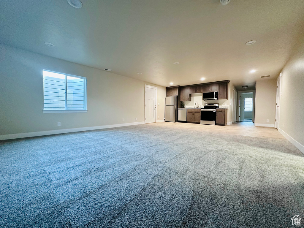 Unfurnished living room featuring light colored carpet and sink