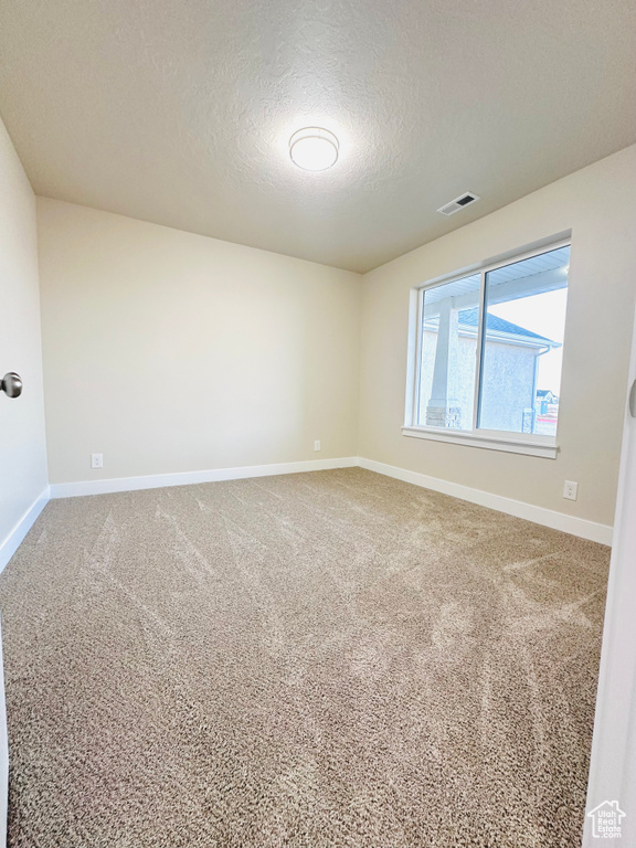 Carpeted empty room featuring a textured ceiling