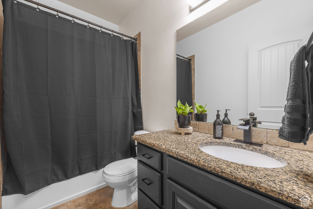 Full bathroom featuring shower / bath combo with shower curtain, tile patterned floors, toilet, and vanity