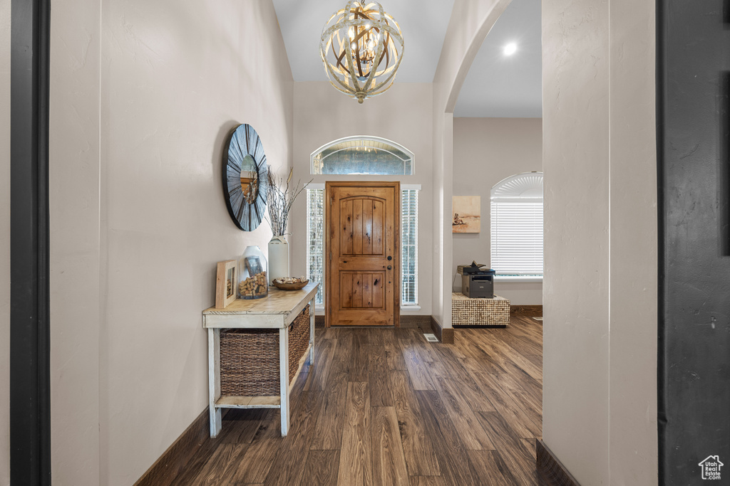 Foyer entrance with a notable chandelier, dark hardwood / wood-style flooring, and high vaulted ceiling