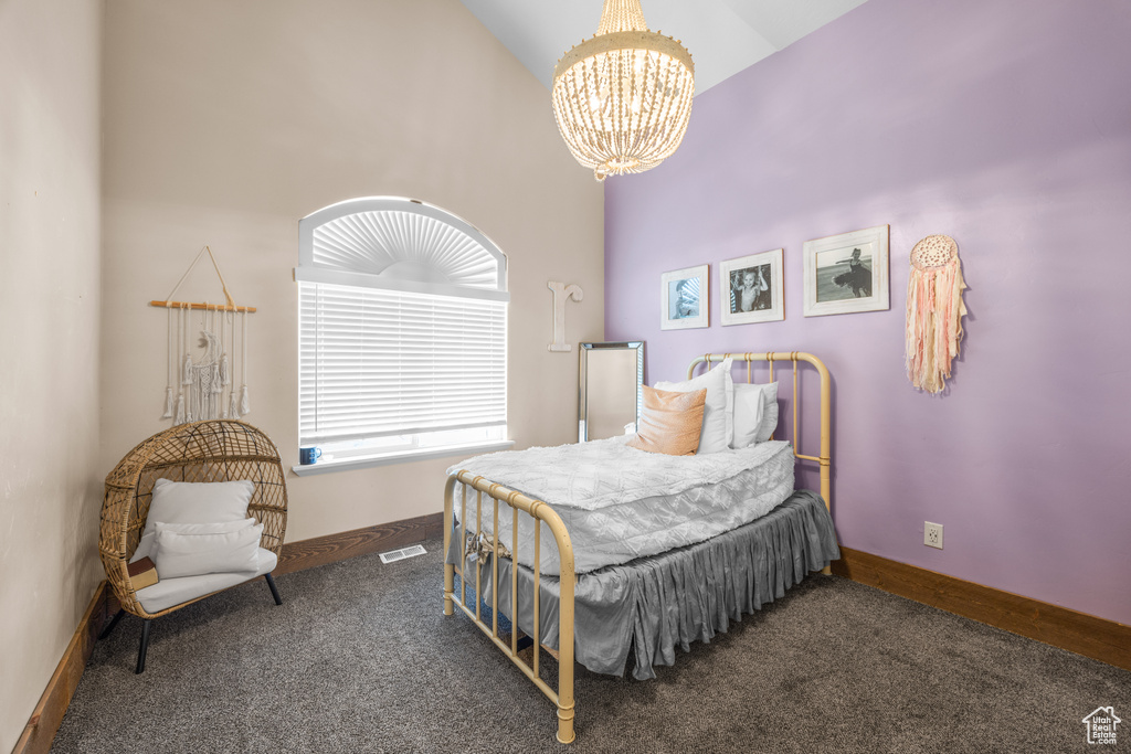 Carpeted bedroom featuring a notable chandelier and high vaulted ceiling