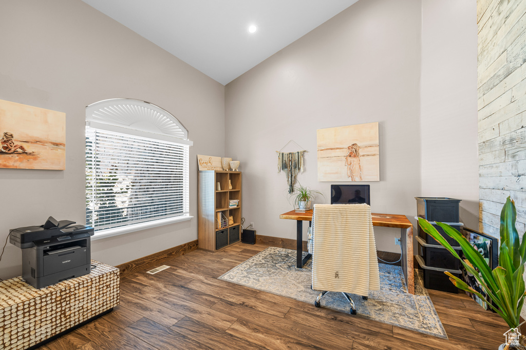 Office area with high vaulted ceiling and hardwood / wood-style floors