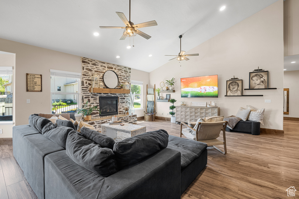 Living room with high vaulted ceiling, a fireplace, ceiling fan, and hardwood / wood-style floors