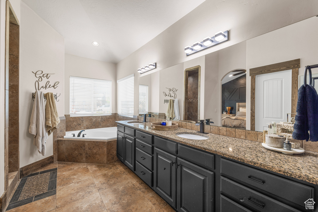 Bathroom featuring tile patterned flooring, tiled bath, and double sink vanity